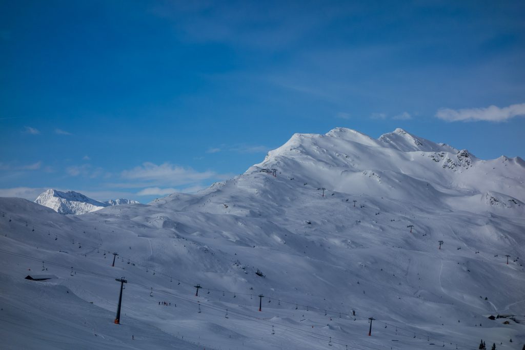 Während das Skigebiet noch im Schatten liegt, werden die ersten Gipfel schon von der Sonne angeschienen